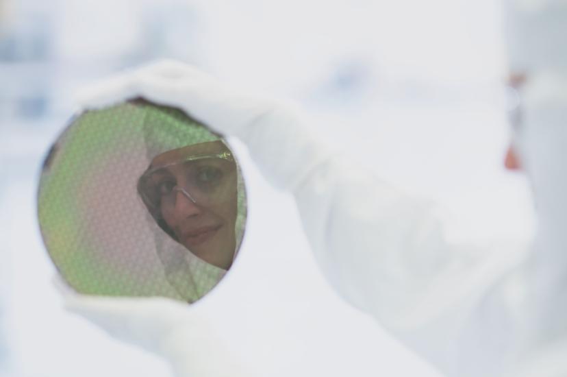 A cleanroom worker holds up an integrated circuit wafer