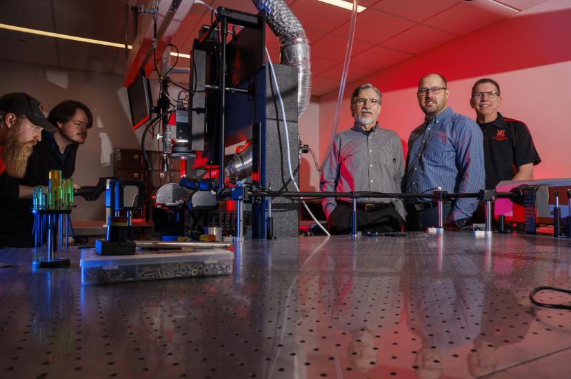 Researchers stand around a light table at the Center for Electro-optics and Functionalized Surfaces, University of Nebraska-Lincoln