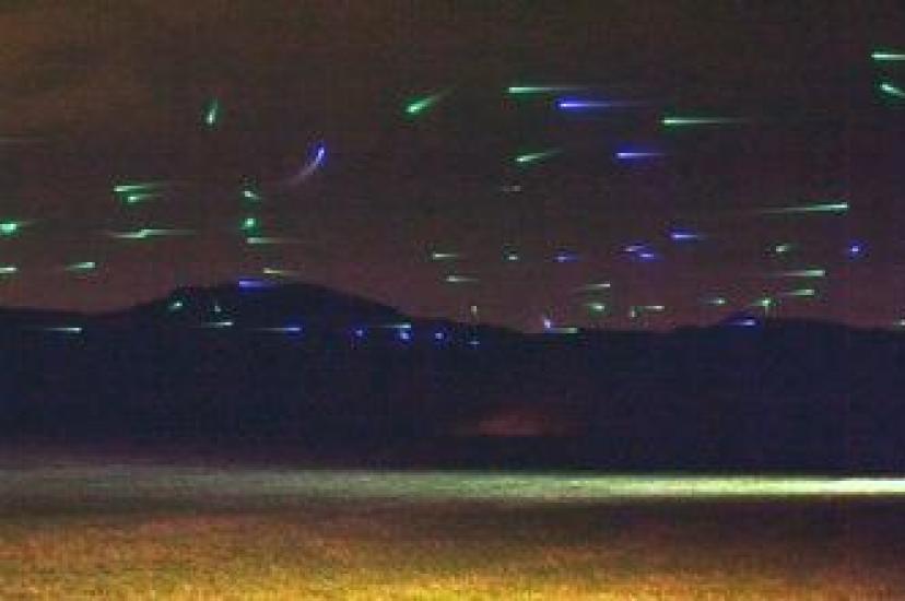 Field experiment with 100 autonomous drones in two layers of decentralised traffic. Colour-coded lights indicate when a drone is in free motion (green), avoiding others (blue), queuing (purple) and has reached its destination (white)