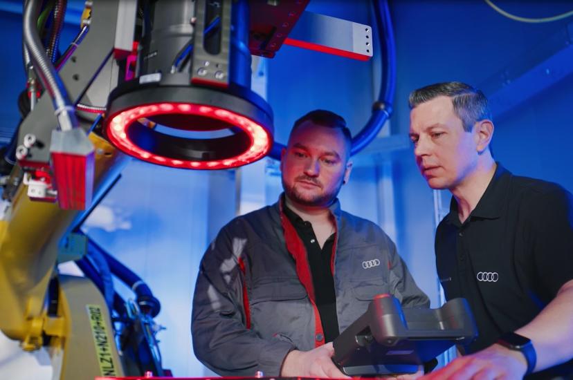 Two men stand behind a large robot arm containing a laser and imaging equipment