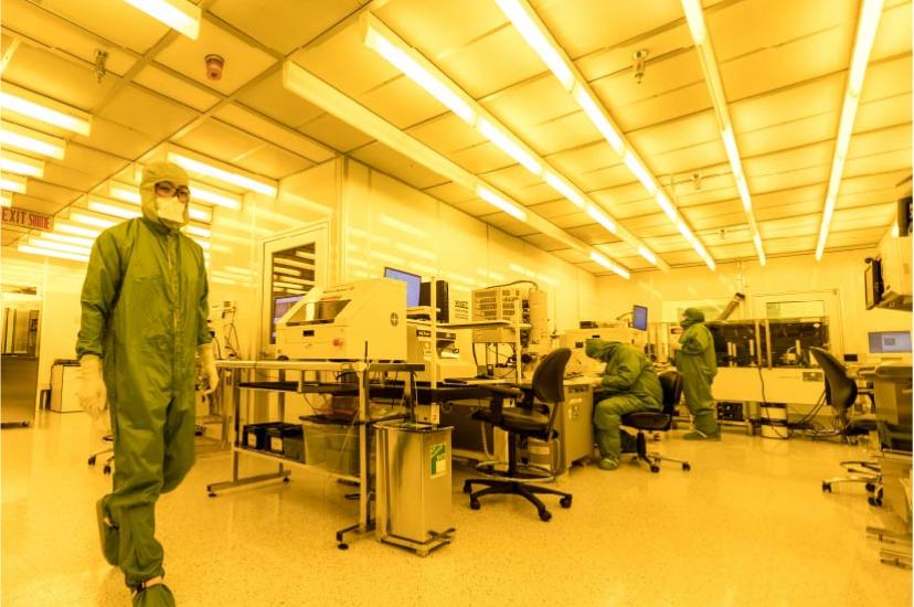 Technician in full PPE walks across a lab at the Canadian Photonics Fabrication Centre