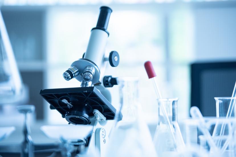 A stock image of a laboratory microscope surrounded by test tubes