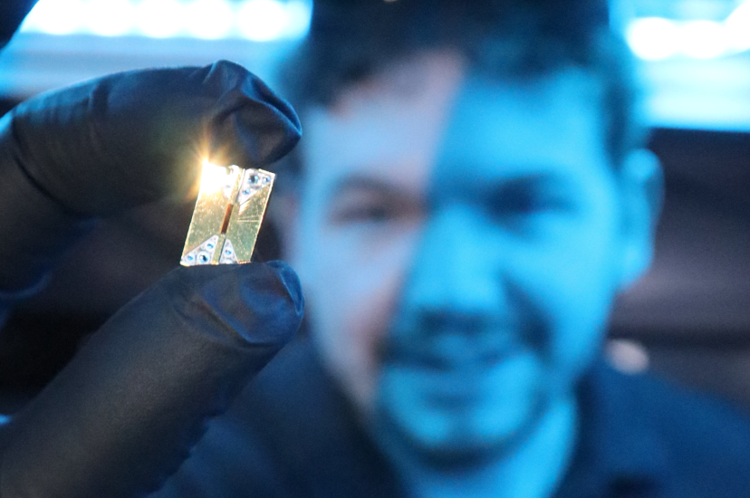 Main holds Photonic integrated circuit chip in the foreground of an image
