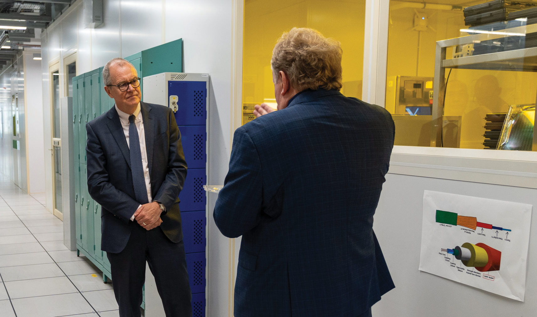 Two men in dark suits, one with his back to the camera, stand in the corridor of Southmpton University's Optoelectronics Research Centre