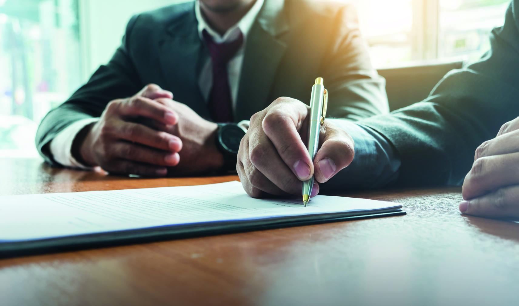Signing a contract with a pen on a desk
