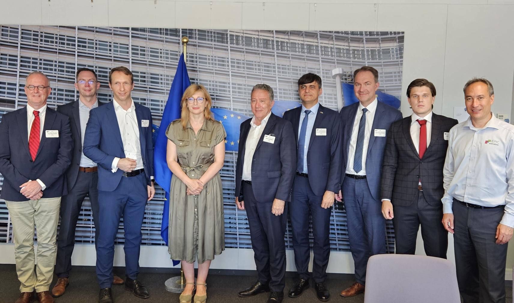A woman flanked by seven men with a European flag in the background