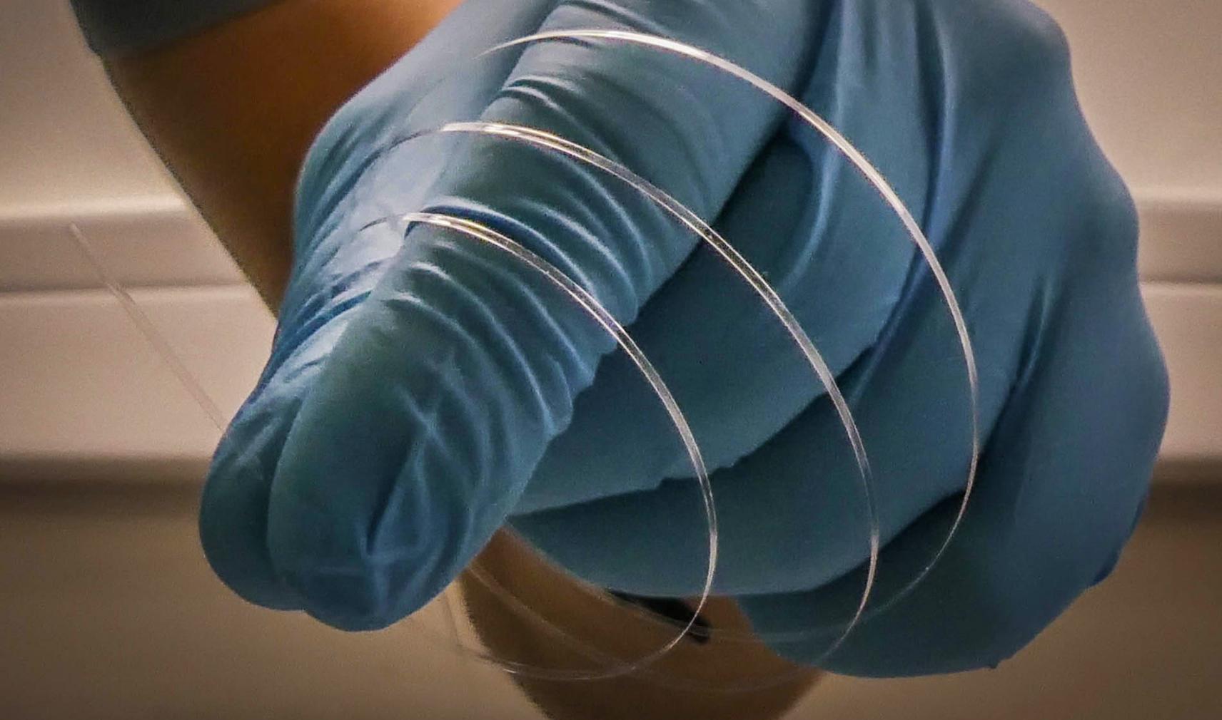 flat optical fibre in gloved hand