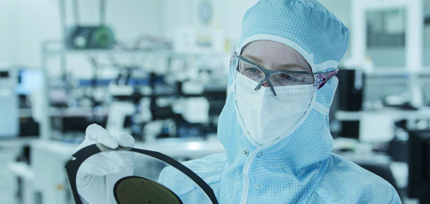 Worker inspecting semiconductor wafer