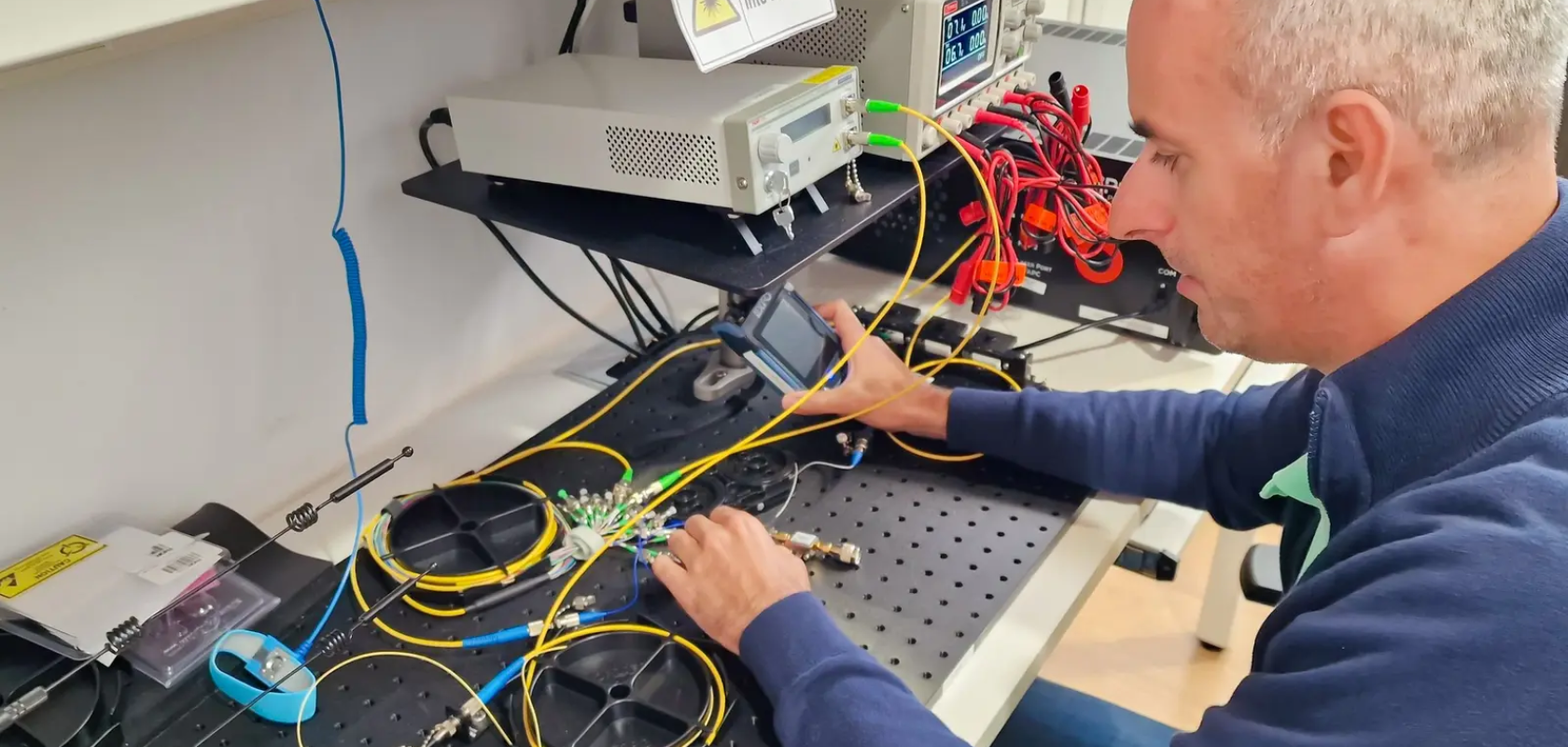 A man sits at a lab bench connecting wires