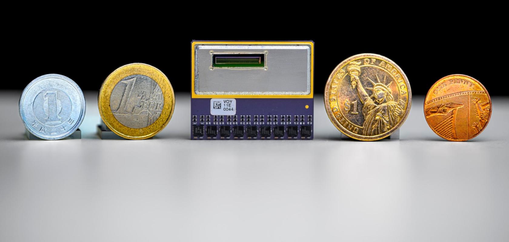 A small integrated circuit next to range of coins and currencies