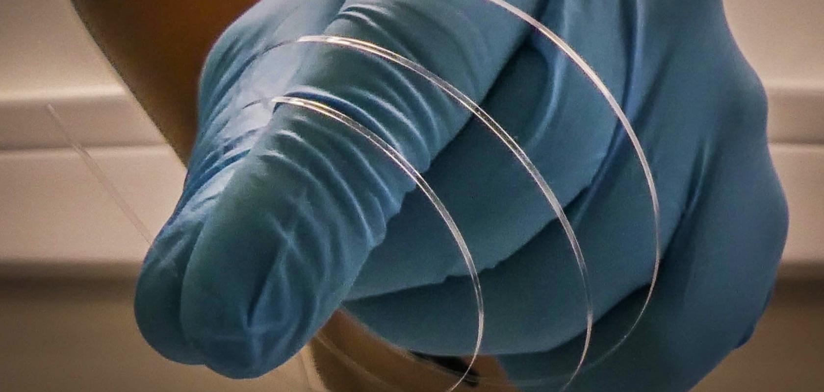 flat optical fibre in gloved hand