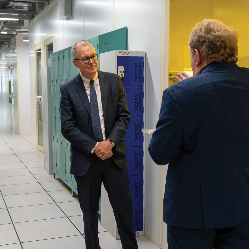 Two men in dark suits, one with his back to the camera, stand in the corridor of Southmpton University's Optoelectronics Research Centre