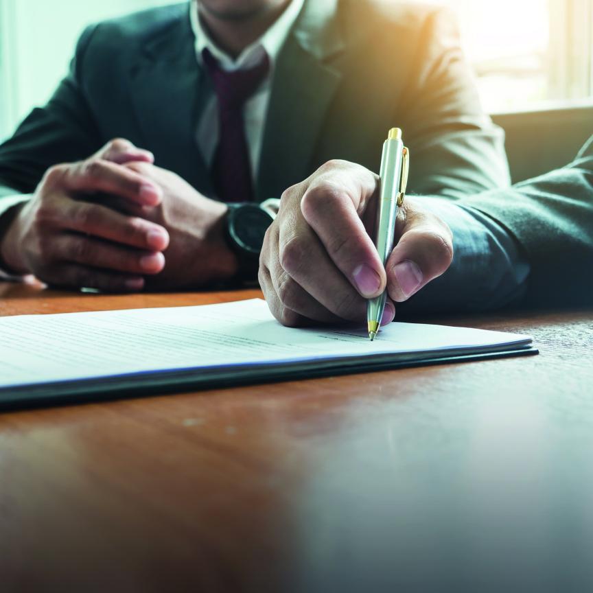 Signing a contract with a pen on a desk