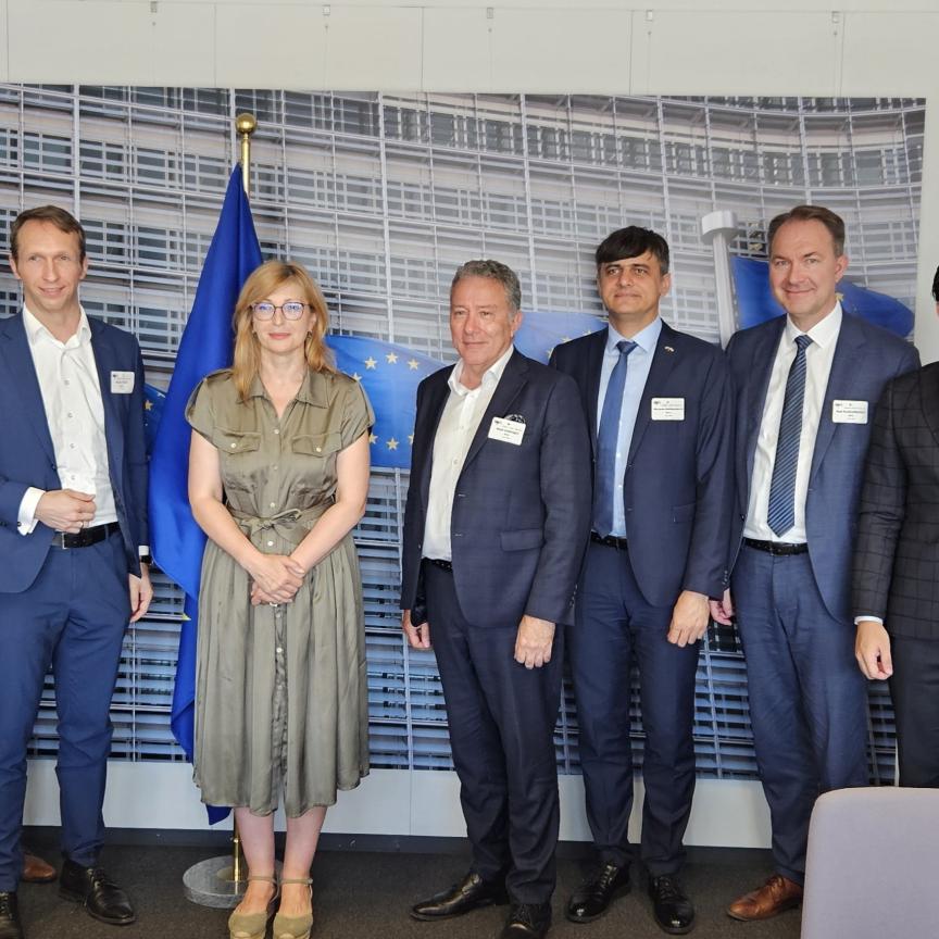 A woman flanked by seven men with a European flag in the background