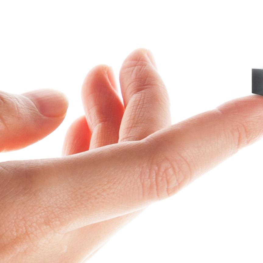 A human hand, on which an outstretched finger holds a tiny black cube