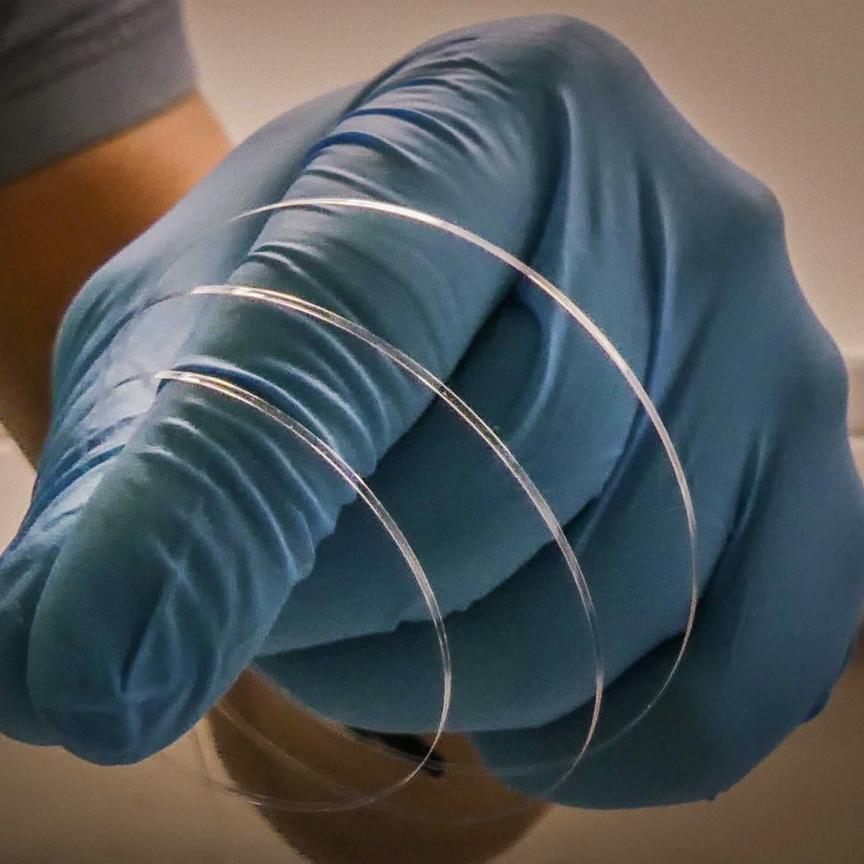 flat optical fibre in gloved hand