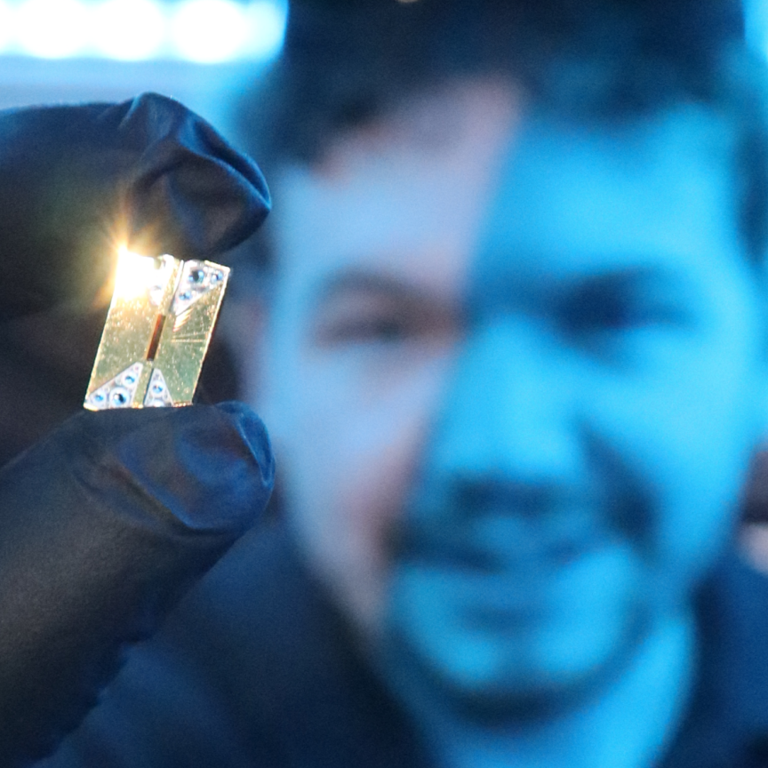 Main holds Photonic integrated circuit chip in the foreground of an image