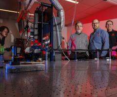 Researchers stand around a light table at the Center for Electro-optics and Functionalized Surfaces, University of Nebraska-Lincoln